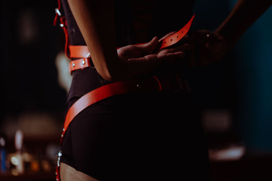 Kobieta zapina skórzany harness na czarny gorset, harness jak nosić